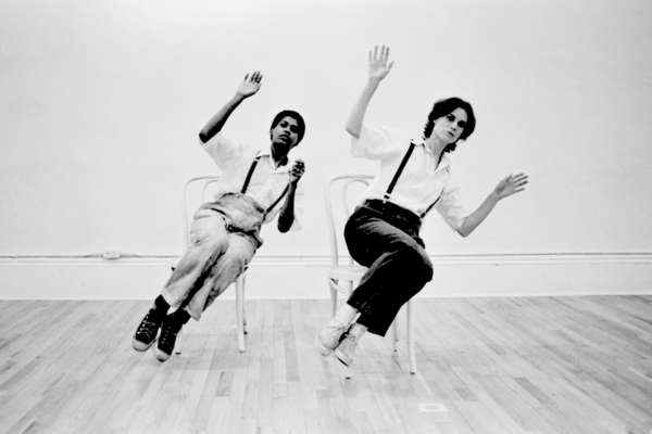 black and white image of two people sitting at a diagonal in chairs with their arms up