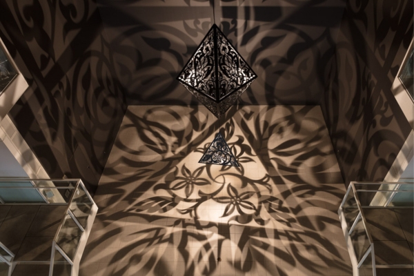artwork by Anila Quayyum Agha featuring a large hanging sculpture that casts decorative light across the Atrium walls
