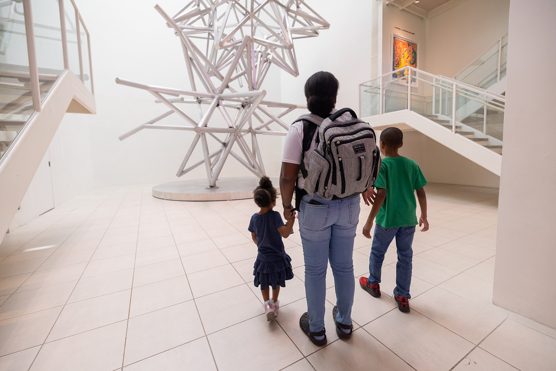 a family of three walks towards Project Atrium: Frank Stella at MOCA Jacksonville