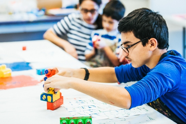 a boy uses toy building blocks as a stamp with paint