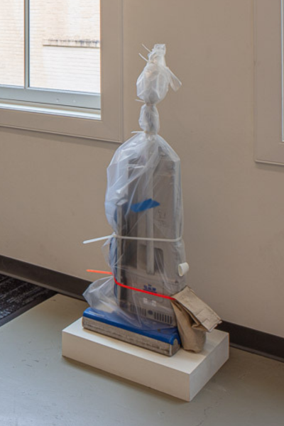 artwork by Brennan Wojtyla featuring a vacuum wrapped in a clear plastic sheet
