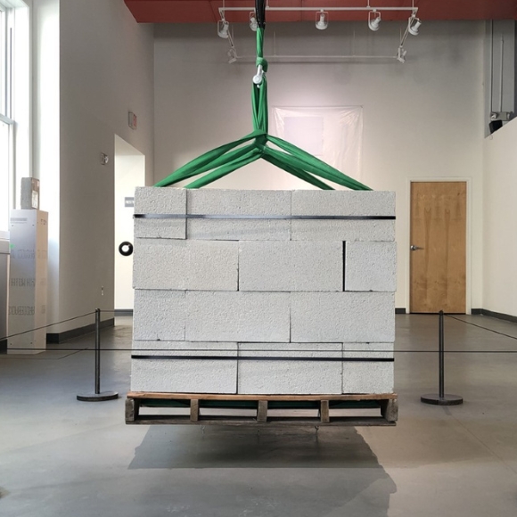 Artwork by Brennan Wojtyla titled One Ton created with cinder blocks, pallet, polyester straps, and a steel saddle