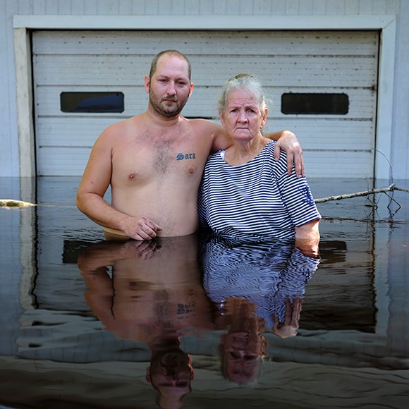 a man and his mother standing waist high in water in front of a garage door