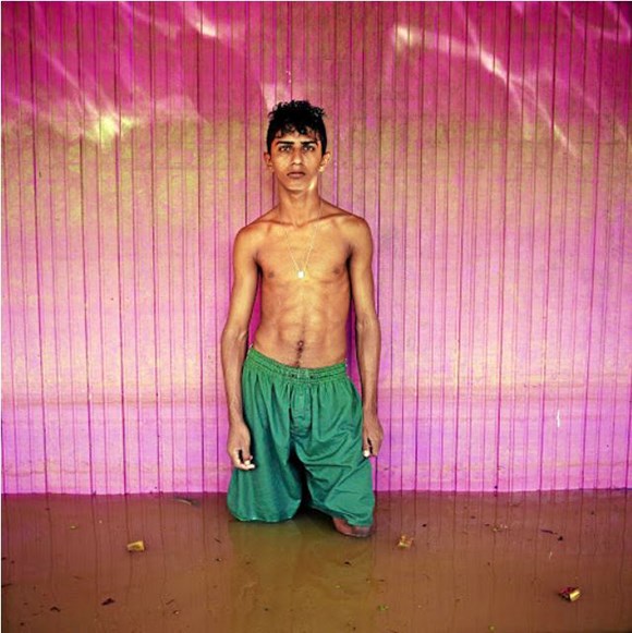 a boy standing in dirty water against a pink wall