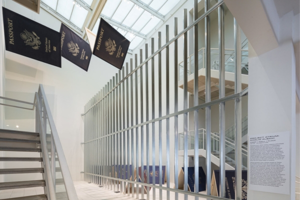 artwork by Khalid Albaih featuring oversized passports hanging from the ceiling and resting on the floor