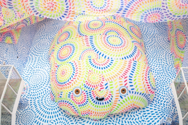 artwork by the art collective Milagros featuring colorful line patterns and an inflated bubble