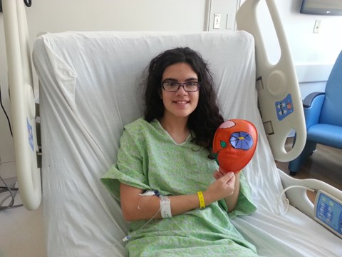 girl in a hospital bed holding her mask