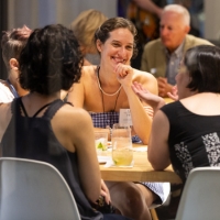 a group of women sitting at a table with drinks and laughing