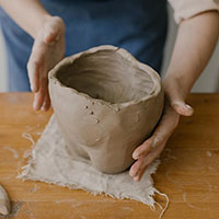 hands molding clay into a bowl