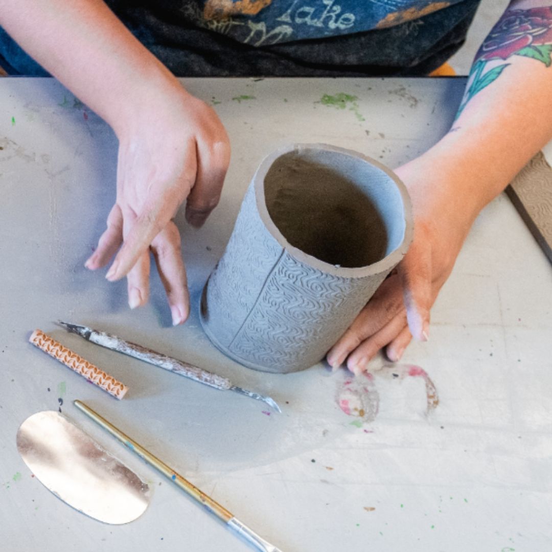 close up of hands working on hand building ceramics 