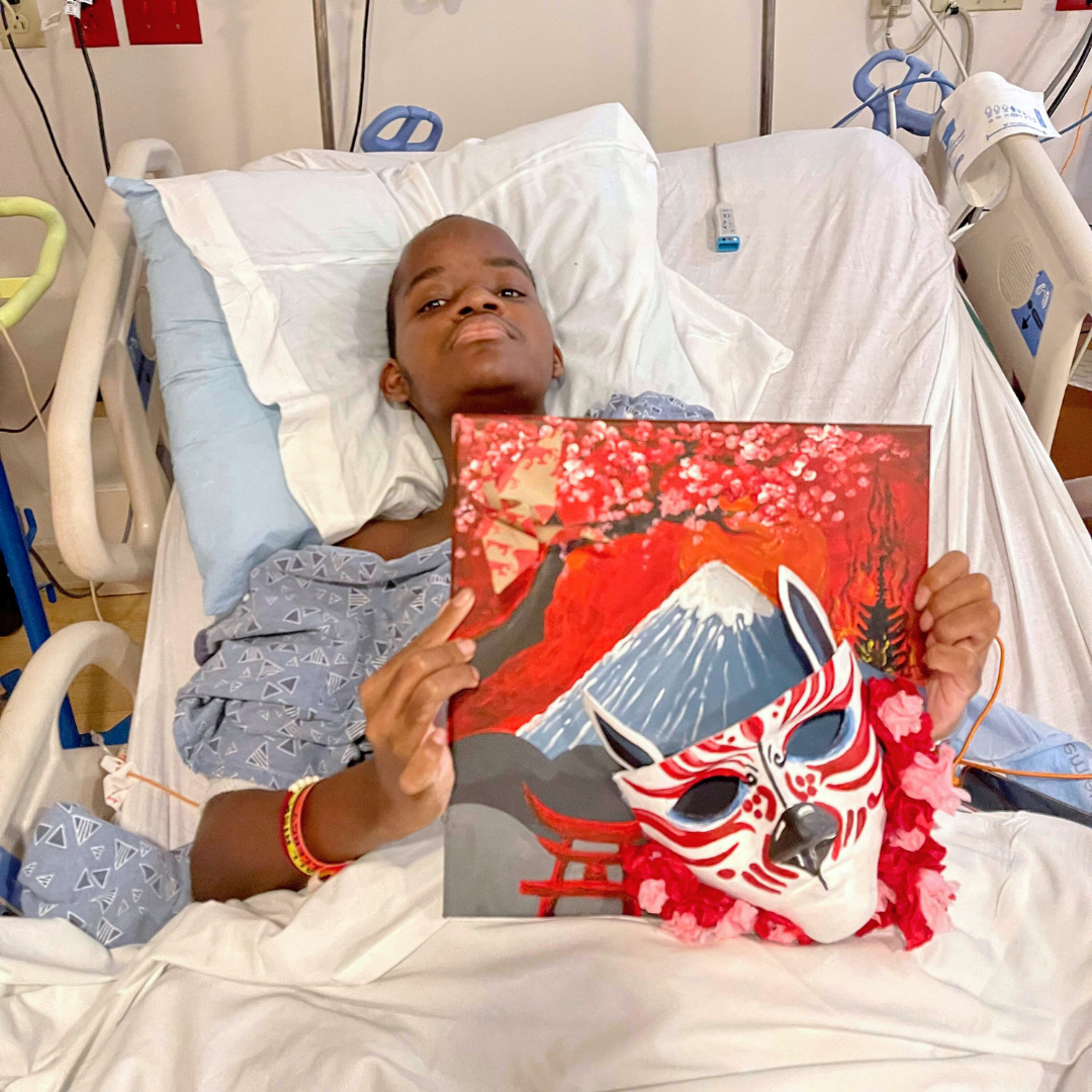 a young artists at Wolfson Children's Hospital holds up his artwork featured in Art with a Heart in Healthcare: Daydreamers