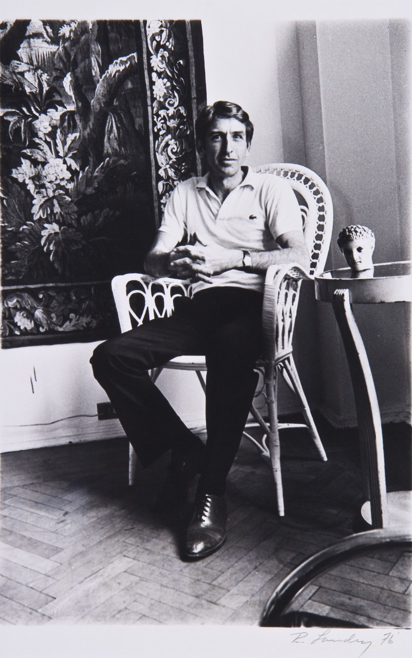 black and white photo of Norman Fisher lounging in a chair in front of painting