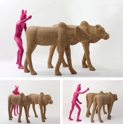 Sculpture of two camels and a pink human with a rabbit head