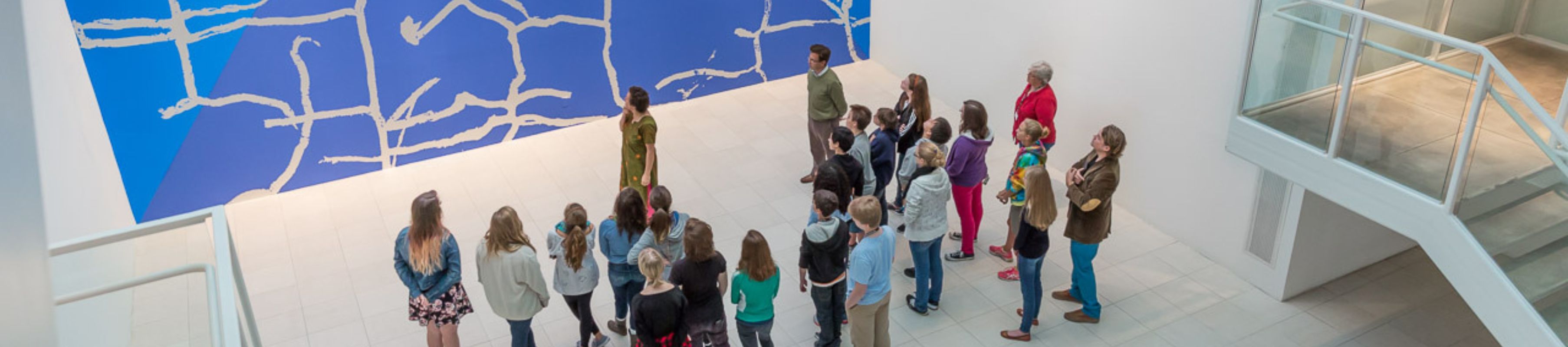 a group of children part of a school tour look up at artwork in the Atrium Gallery at MOCA