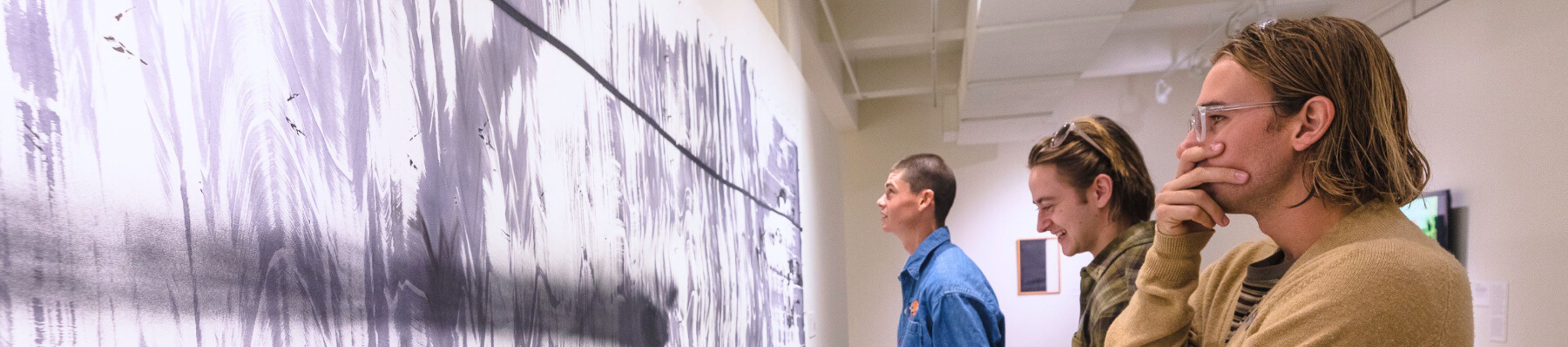 three UNF students look at work in MOCA's galleries